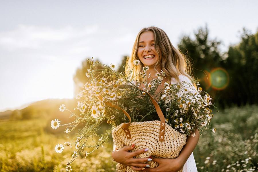 Fiatal, mosolygós lány a szabadban tavaszi virágokkal a kezében.